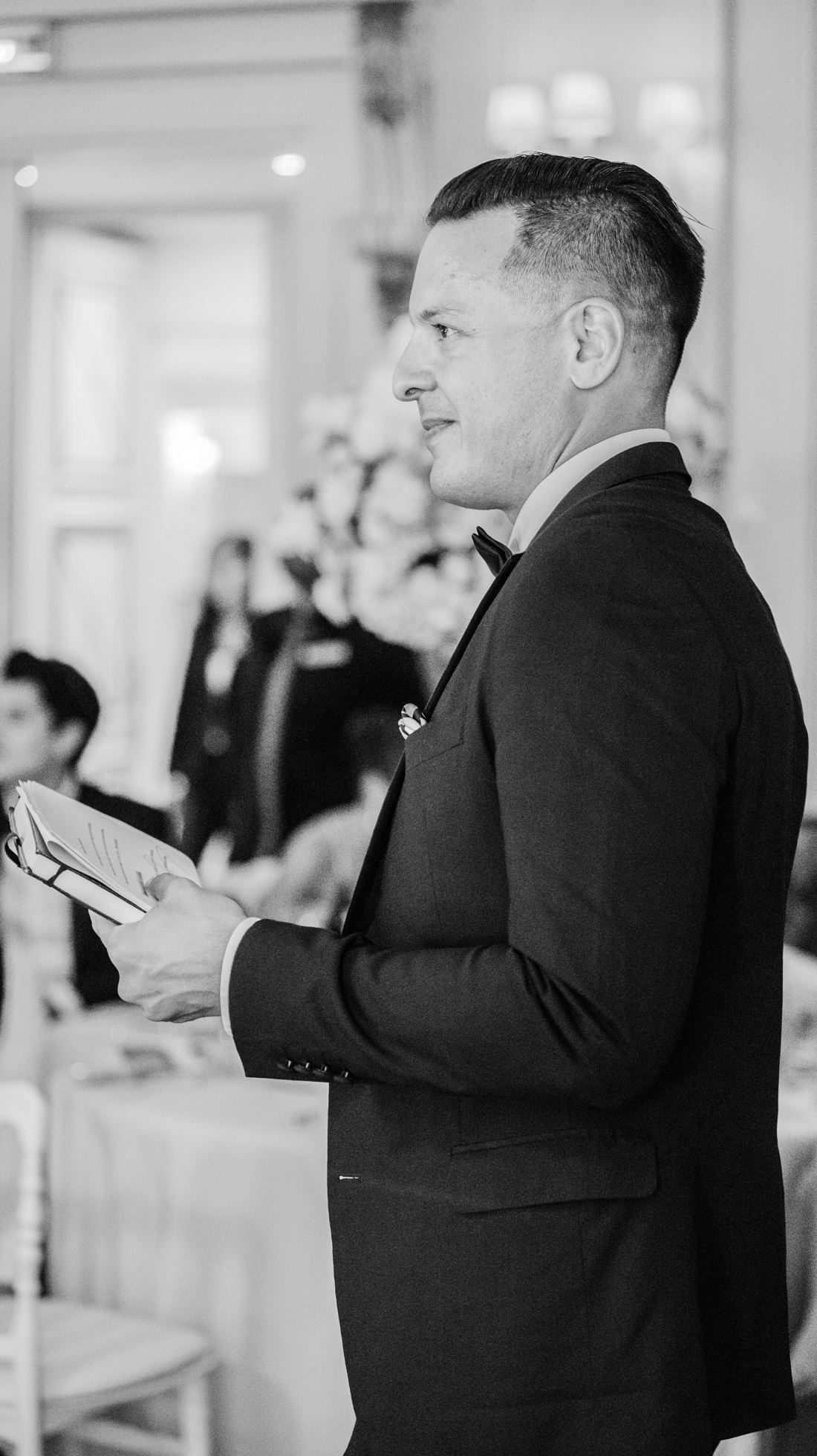 Naïm Terrache in profile, holding his notes, in a function room, black and white