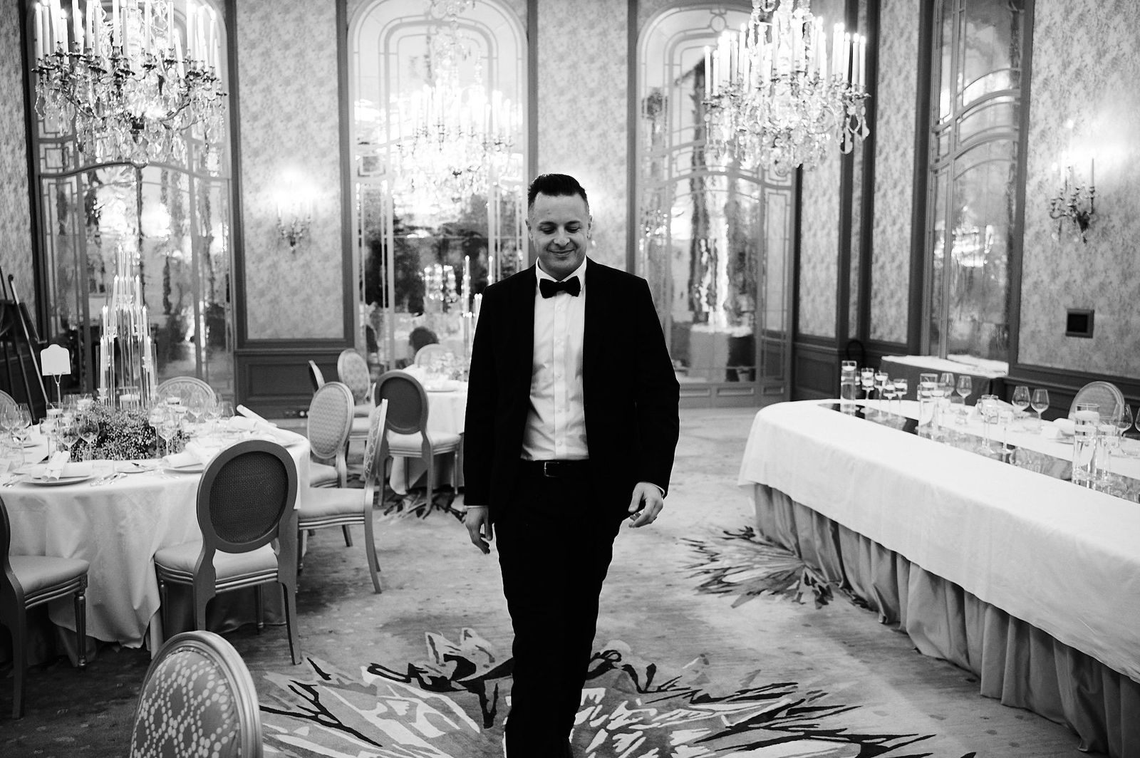 Naïm Terrache walking through a palace ballroom before the guests arrive, black and white