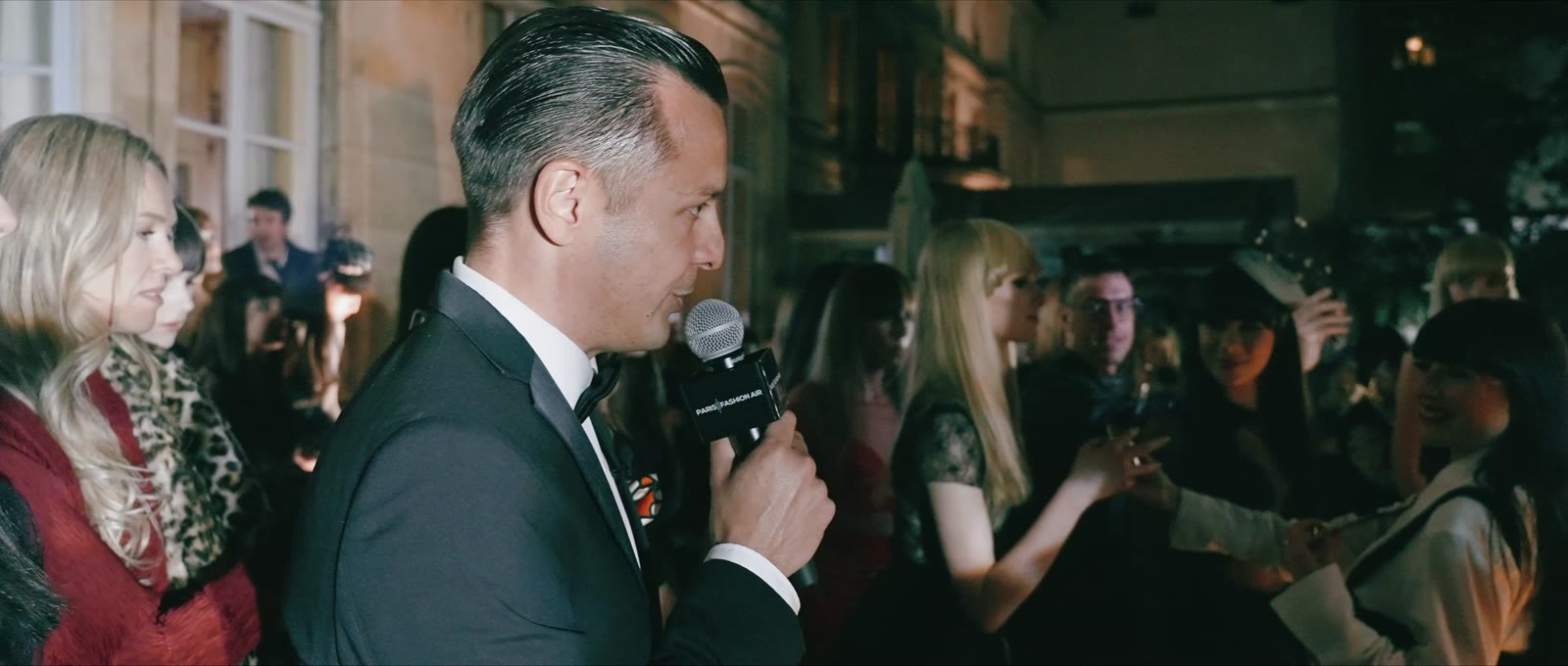 Naïm Terrache hosting among guests at a fashion show, microphone in hand